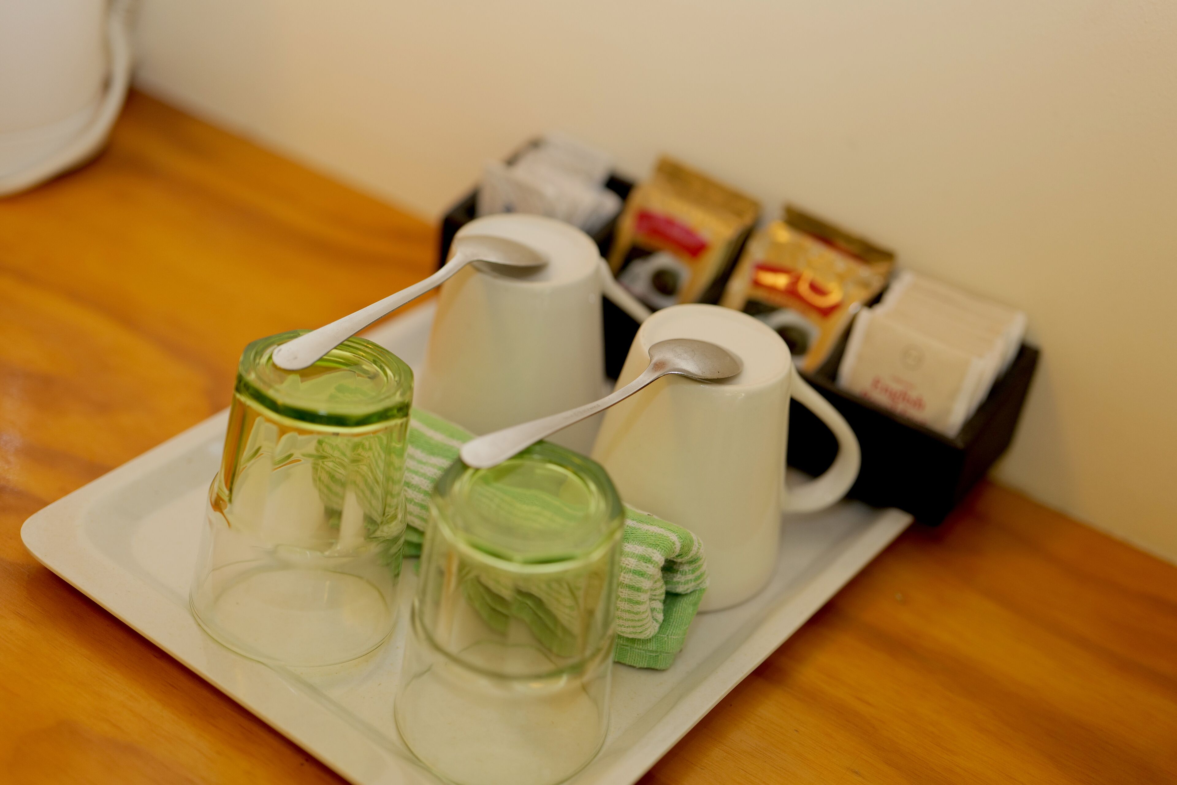 A tray with a glass, a white mug, and a spoon, along with some packaged goods on a wooden table.