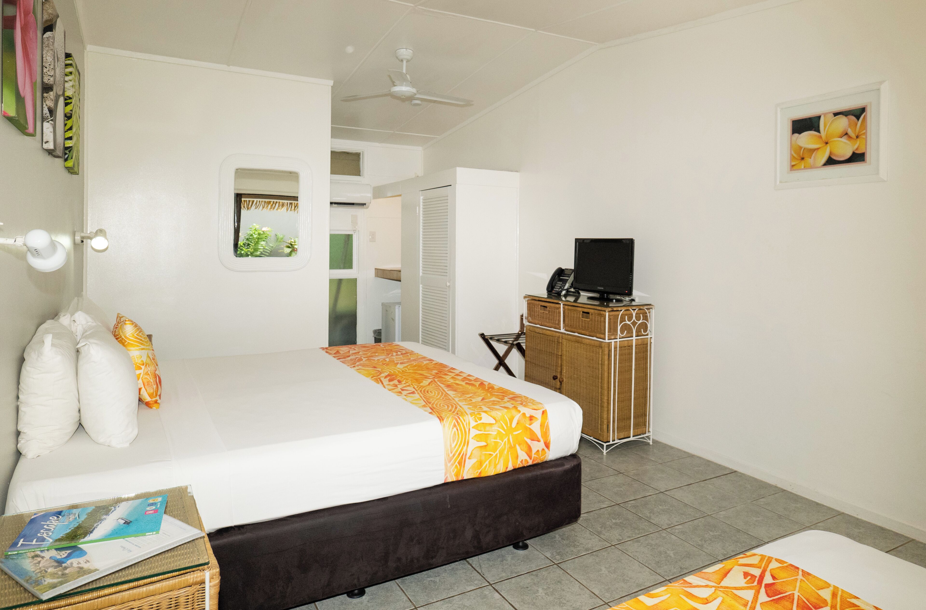 A hotel room with a bed, a television, a desk, and a window.
