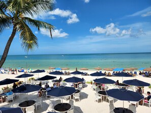 A beachside restaurant with outdoor seating and umbrellas, overlooking the ocean. - Vanderbilt Beach Resort (Naples)