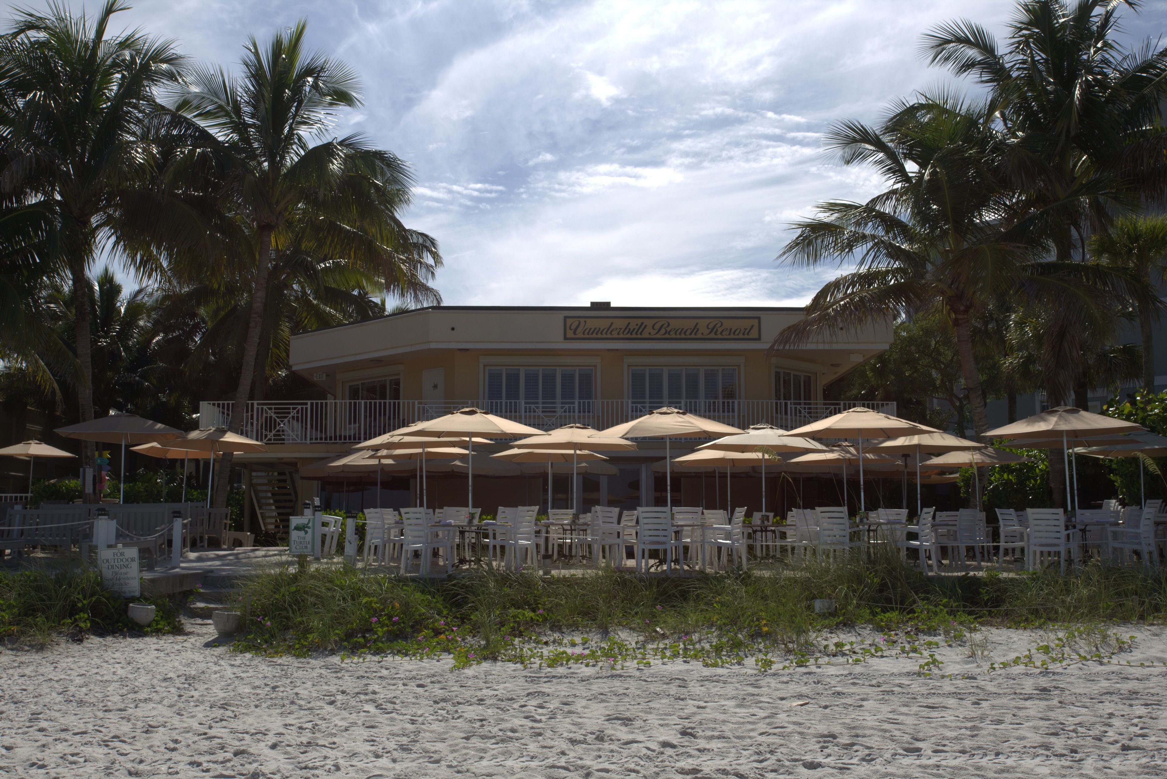 A beachfront resort with outdoor seating and palm trees.