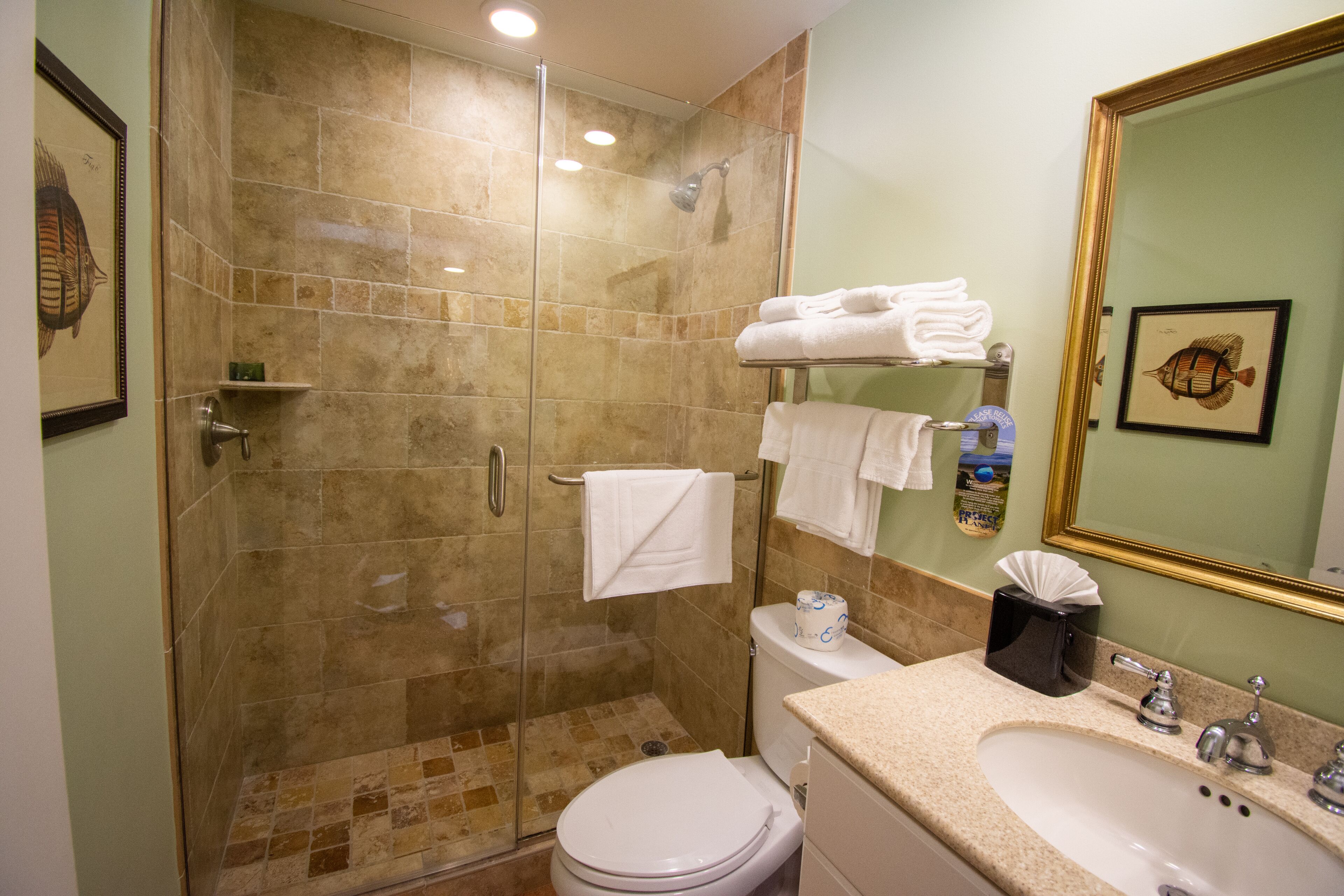 Une salle de bain avec une douche à parois de verre, des toilettes, un lavabo avec un miroir et des serviettes sur un porte-serviettes.