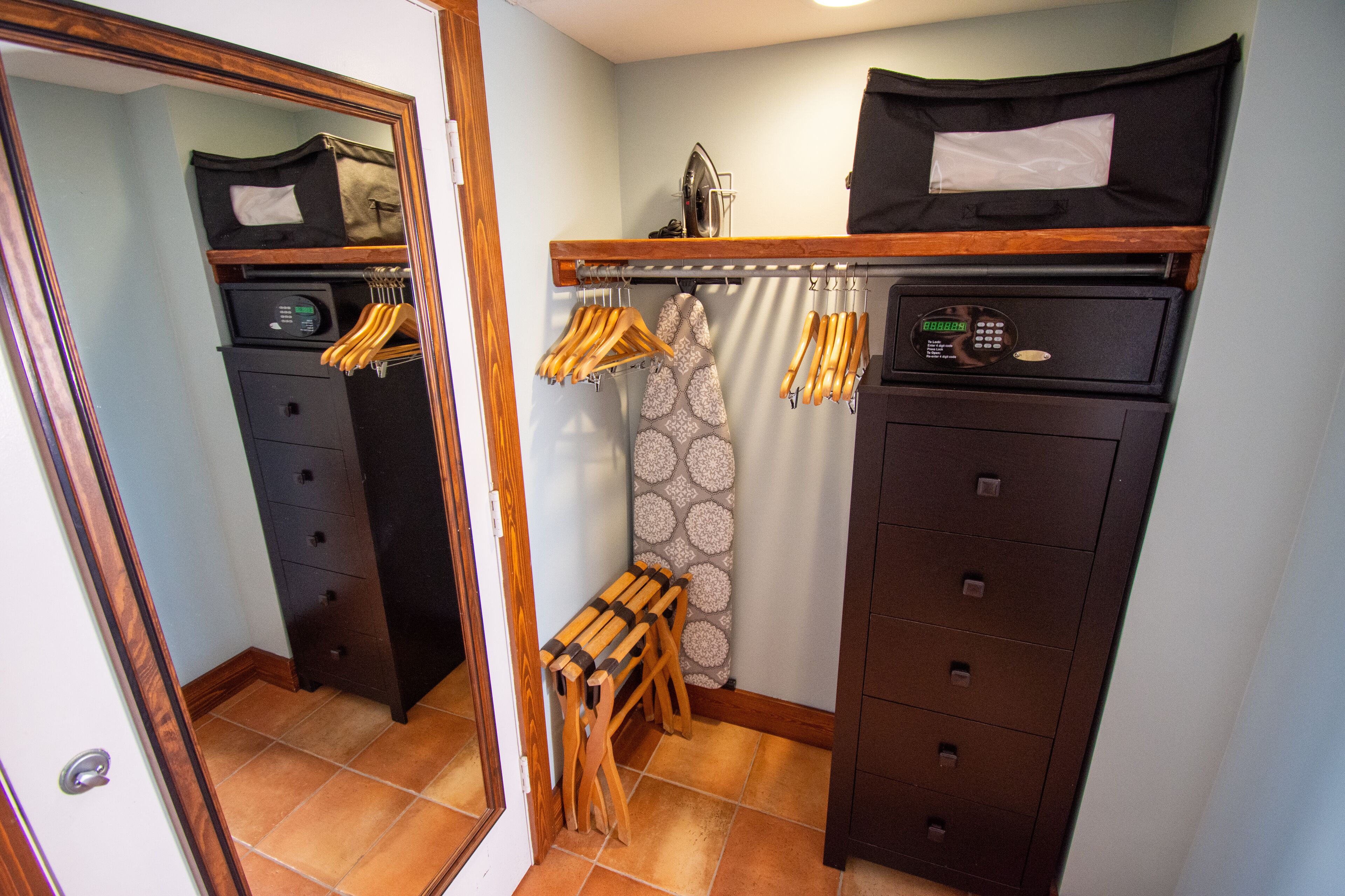 A compact kitchen with a built-in microwave, a small oven, and a coffee maker on the countertop. There is a wooden bench and a hanging rack with utensils.