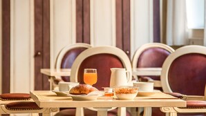 A breakfast table set with a croissant, a bowl of cereal, a cup, a glass of orange juice, and a pitcher. - Hotel La Pace (Pontedera)