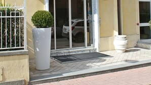 A hotel entrance with a sign reading "hotel LA PACE," a glass door, and a potted plant in front. - Hotel La Pace (Pontedera)