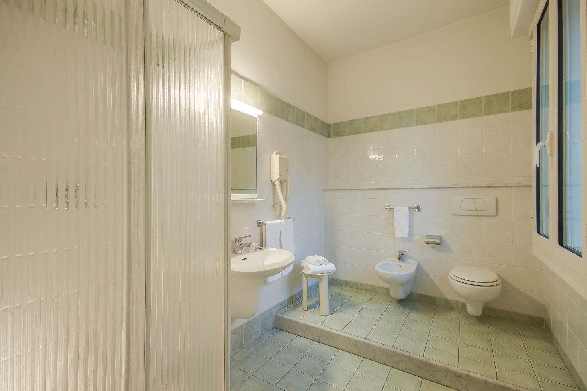 Un baño con lavamanos, bidé, inodoro y espejo.