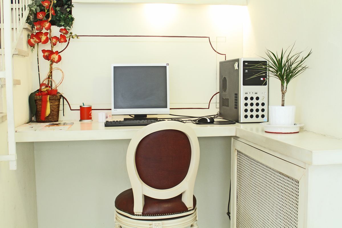 Ein kleines Büro mit einem Computer, einem Stuhl, einer Topfpflanze und einer dekorativen Vase.