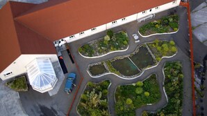 An aerial view of a building with a red roof, surrounded by landscaped gardens and a parking area. - Orkneylodge (Orphir)