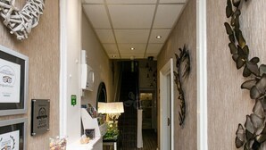 Un couloir d’hôtel orné de cadres contenant des récompenses, un comptoir de réception, un lustre et des œuvres d’art décoratives murales.