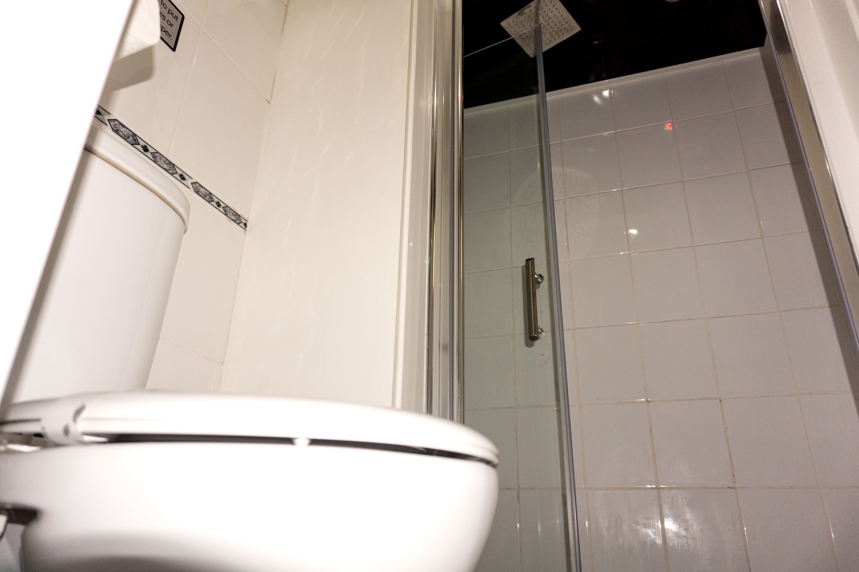 A bathroom with a toilet, a shower area, and a tiled floor.