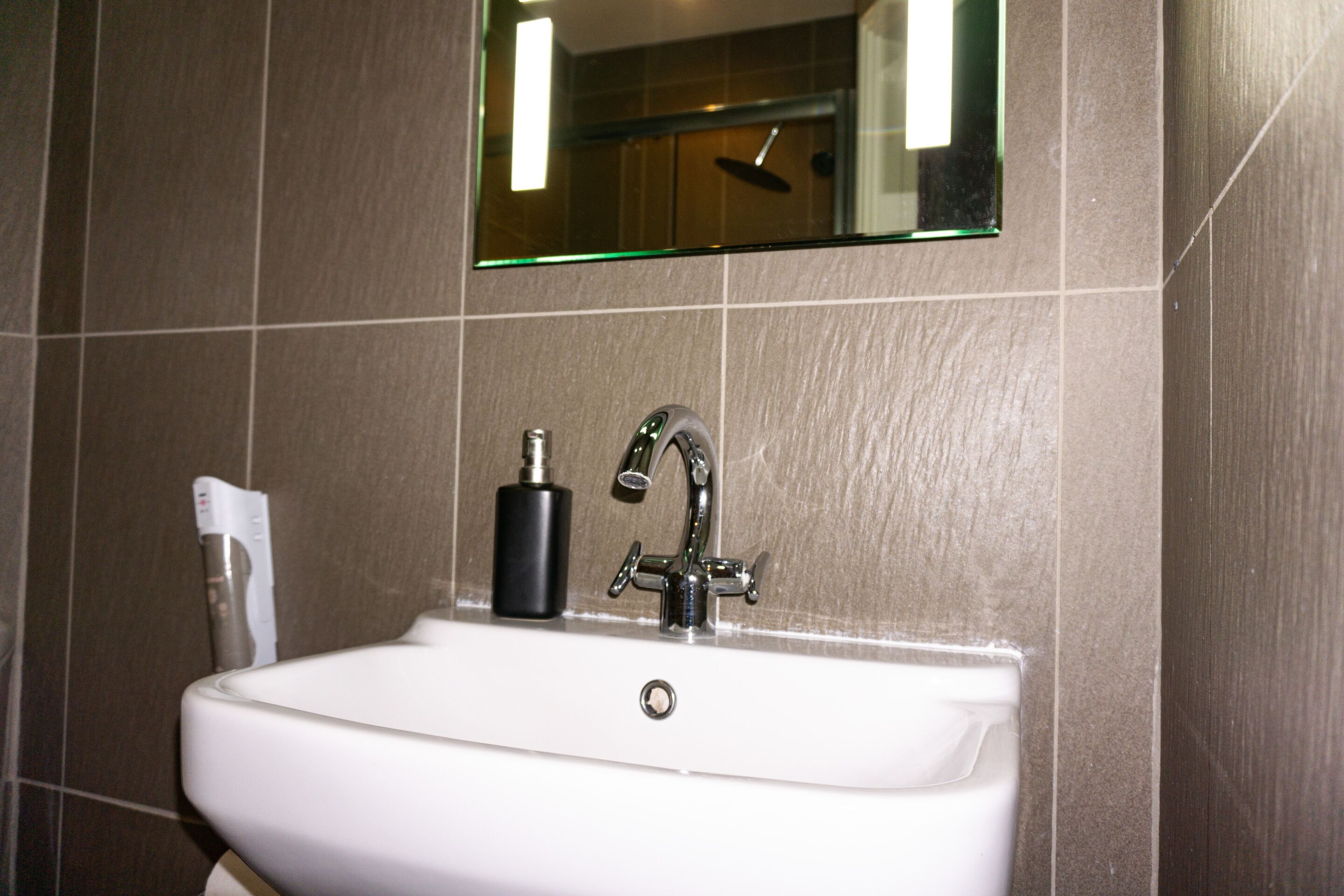 A bathroom sink with a modern faucet and a soap dispenser.