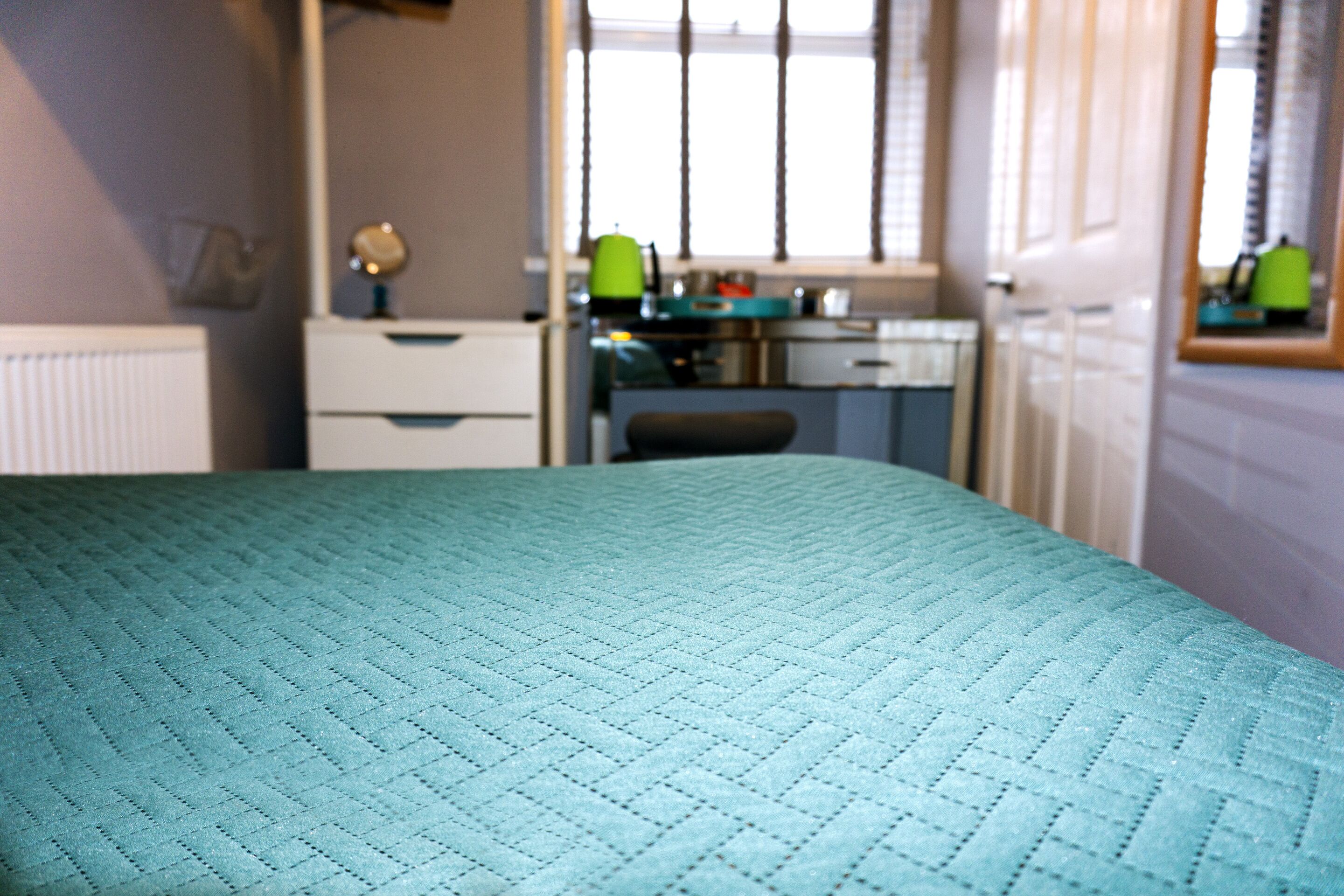 A bedroom with a bed, a desk, and a chair.