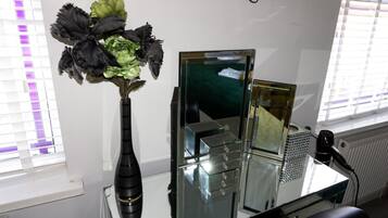 A room with a mirror, a vase with flowers, and a radiator.