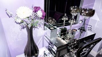 A mirror reflecting a table with a vase of flowers, a decorative box, and a candle holder.