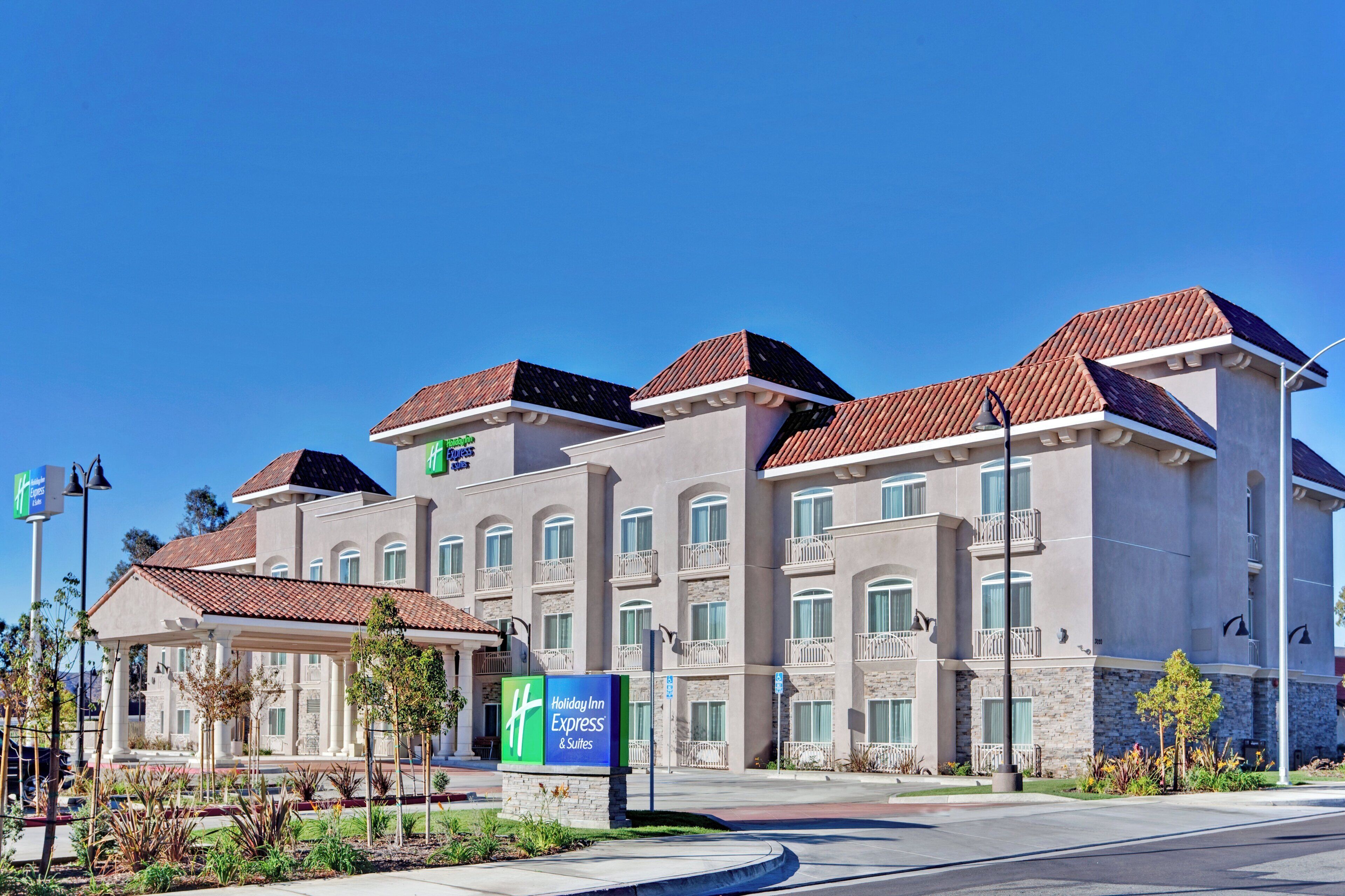 A Holiday Inn Express hotel with a modern architectural design, featuring multiple balconies and a clear blue sky.
