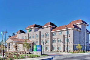 Un hôtel Holiday Inn Express doté d’une architecture moderne, avec de nombreux balcons et une vue sur un ciel d’un bleu éclatant.