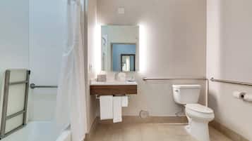Un baño moderno con bañera, inodoro, lavamanos con espejo y cortina de ducha.