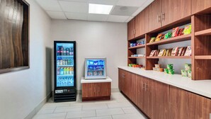 A kitchenette area with a refrigerator, a microwave, and shelves stocked with snacks and beverages. - Holiday Inn Express Hotel & Suites Banning by IHG (Banning)