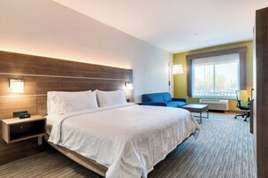 Habitación de hotel con una cama grande, mesitas de noche, un escritorio, una silla y ventana con vistas.