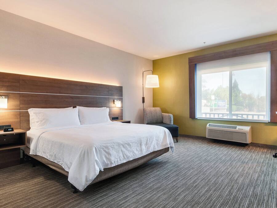 Habitación de hotel con una cama grande, mesitas de noche, una silla, una ventana con vistas y un calefactor de pared.