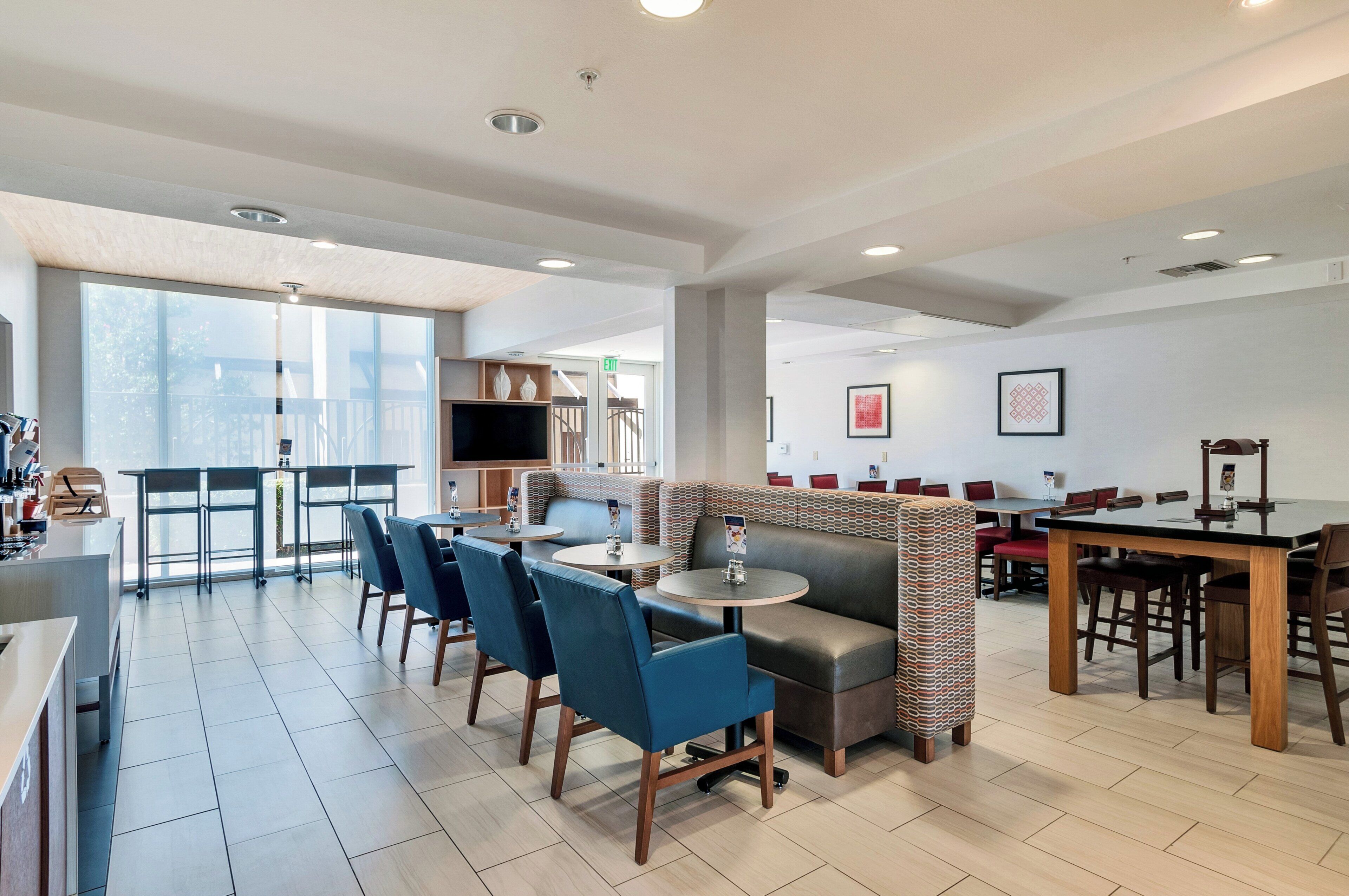 A modern restaurant with a bar area, seating arrangements, and a view of the outdoors.