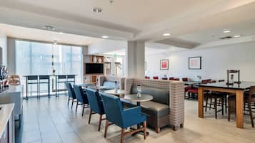 A modern restaurant with a bar area, seating arrangements, and a view of the outdoors.