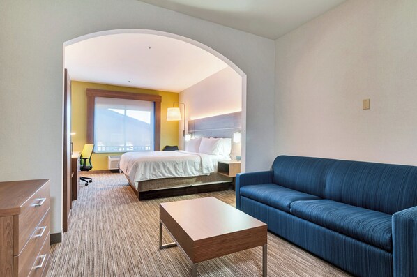A hotel room with a bed, a blue sofa, a wooden nightstand, and a desk. - Holiday Inn Express Hotel & Suites Banning by IHG (Banning)