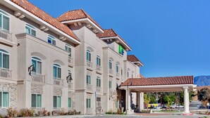 A multi-story hotel with a classic architectural style, featuring a covered entrance and a clear view of the surrounding landscape. - Holiday Inn Express Hotel & Suites Banning by IHG (Banning)
