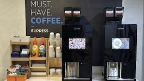 A coffee station with two espresso machines, a sign reading "MUST. HAVE. COFFEE.", and various coffee pods and cups. - Holiday Inn Express Troutville by IHG (Troutville)