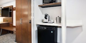 Uma cozinha compacta equipada com micro-ondas, cafeteira e pequena geladeira.