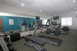 Un gimnasio con cintas de correr, elípticas y equipo de pesas.