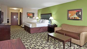 A hotel room with a bed, a sofa, a desk, and a patterned carpet.