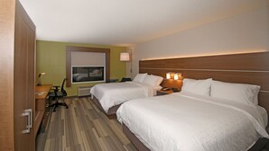 Hotellihuone, jossa on kaksi sänkyä, työpöytä, tuoli, lamppu ja ikkuna.