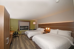 Quarto de hotel com duas camas, uma escrivaninha, uma cadeira, um abajur e uma janela.