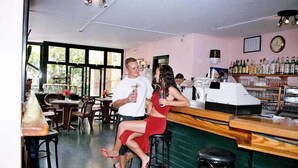 A bar area with wooden stools, a counter, and a variety of bottles. - Fresh Corralejo Garden (La Oliva)