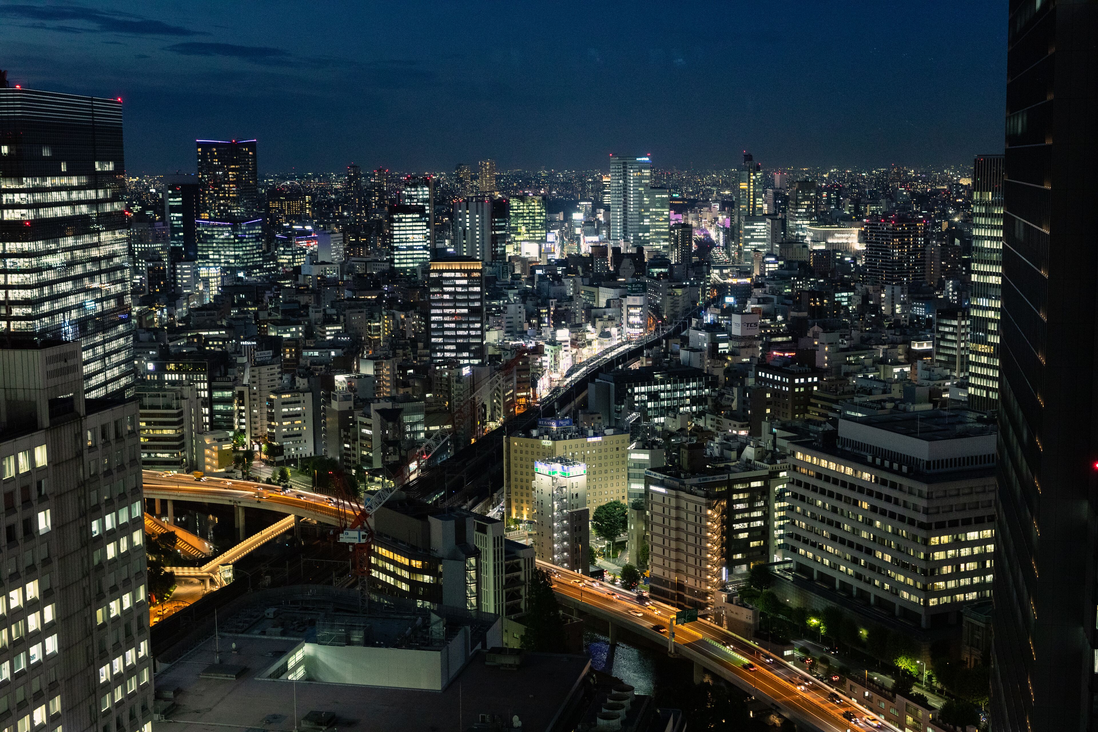 A nighttime cityscape with illuminated buildings and a busy highway.