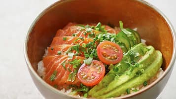 Eine Schüssel mit Lachs, Avocado und Tomaten.
