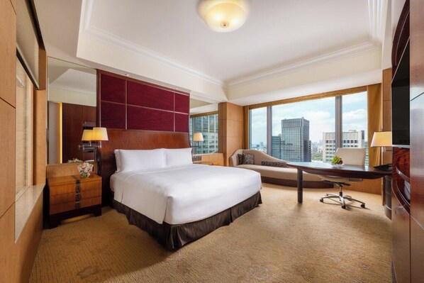 A hotel room with a large bed, a desk, a chair, a sofa, a large window with a city view, and a mirror. - Shangri-La Tokyo (Tokyo)