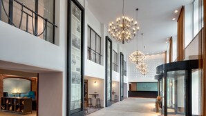 A spacious hotel lobby with high ceilings, large windows, and modern chandeliers. - Hermitage Hotel Prague (Prague)