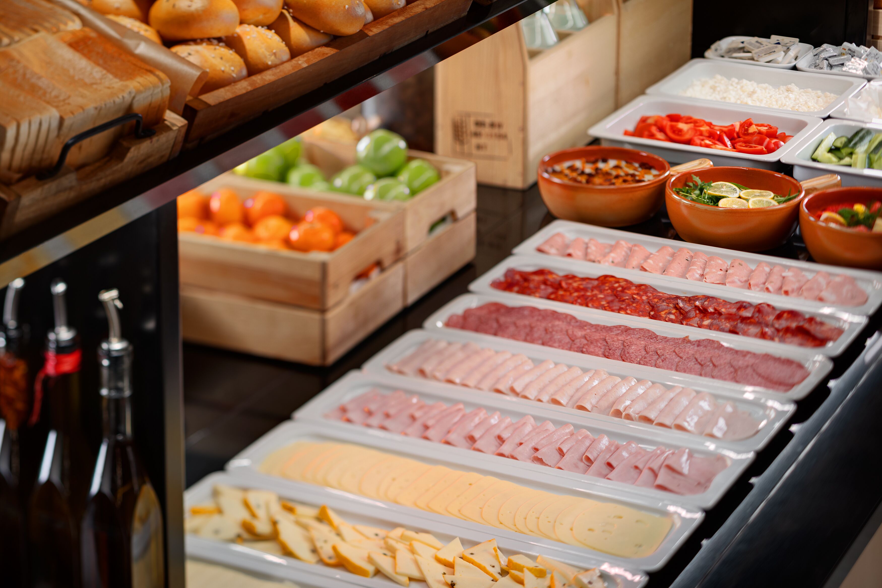 A buffet with various food items including meats, cheeses, and fruits.