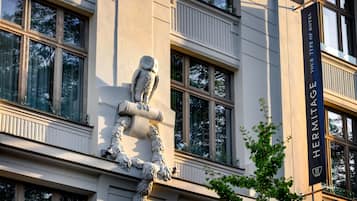 A building facade with a large owl sculpture, multiple windows, and a banner reading "HERMITAGE YOUR TYPE OF HOTEL".
