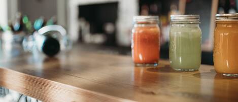 A bar counter with three glass jars containing different colored beverages.