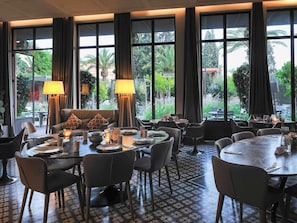 Ein Restaurant mit groĂen Fenstern, gedeckten Tischen und einem gemusterten Boden.