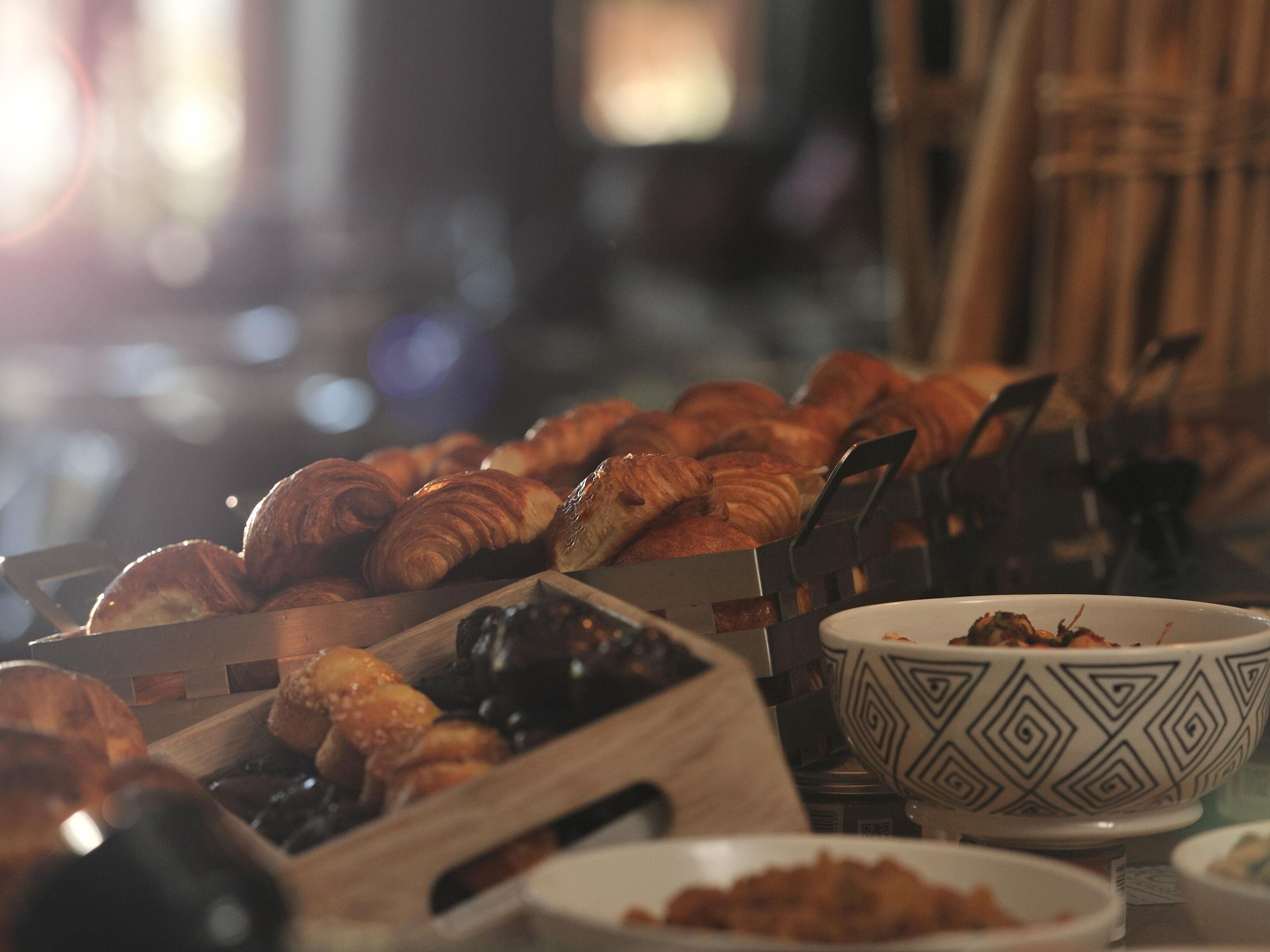 A variety of baked goods displayed on a table, including croissants and other pastries.