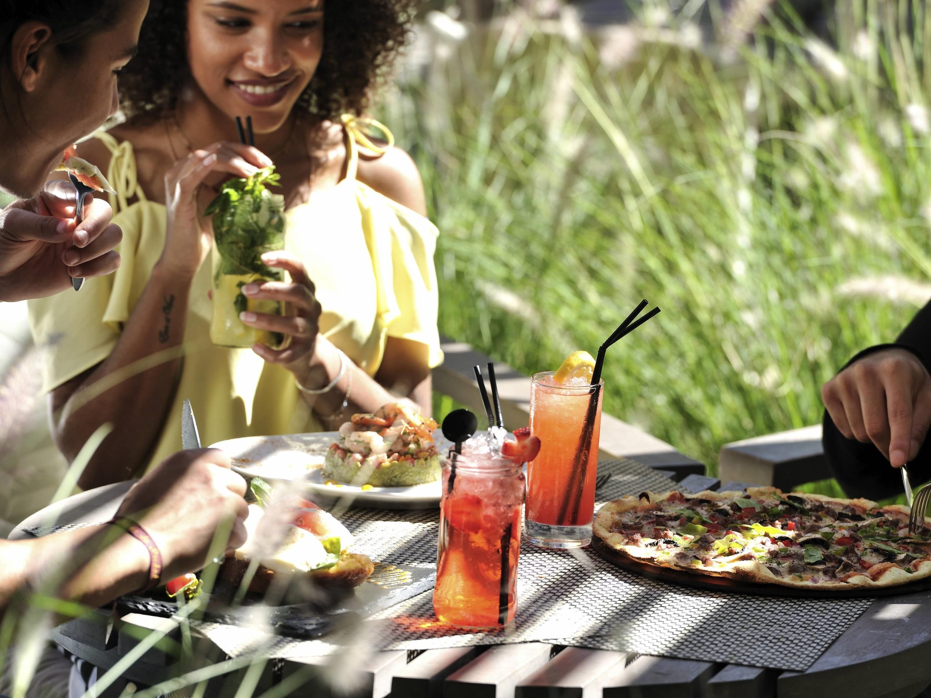 Une table avec de la nourriture et des boissons, une pizza et un verre avec une paille et une tranche de citron.