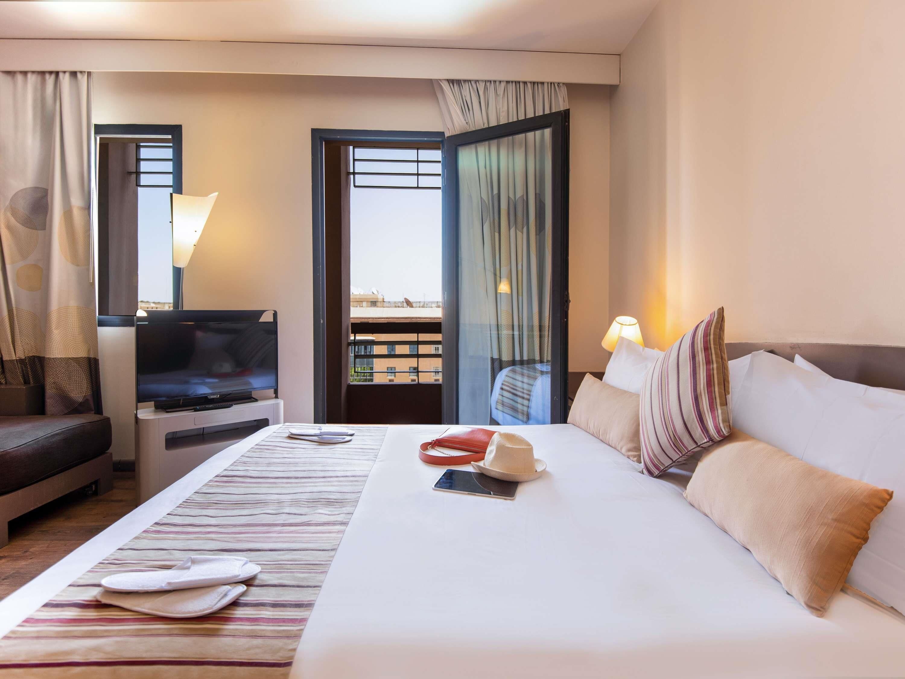 Une chambre d’hôtel avec un lit, une télévision, un bureau et une vue sur l’extérieur.
