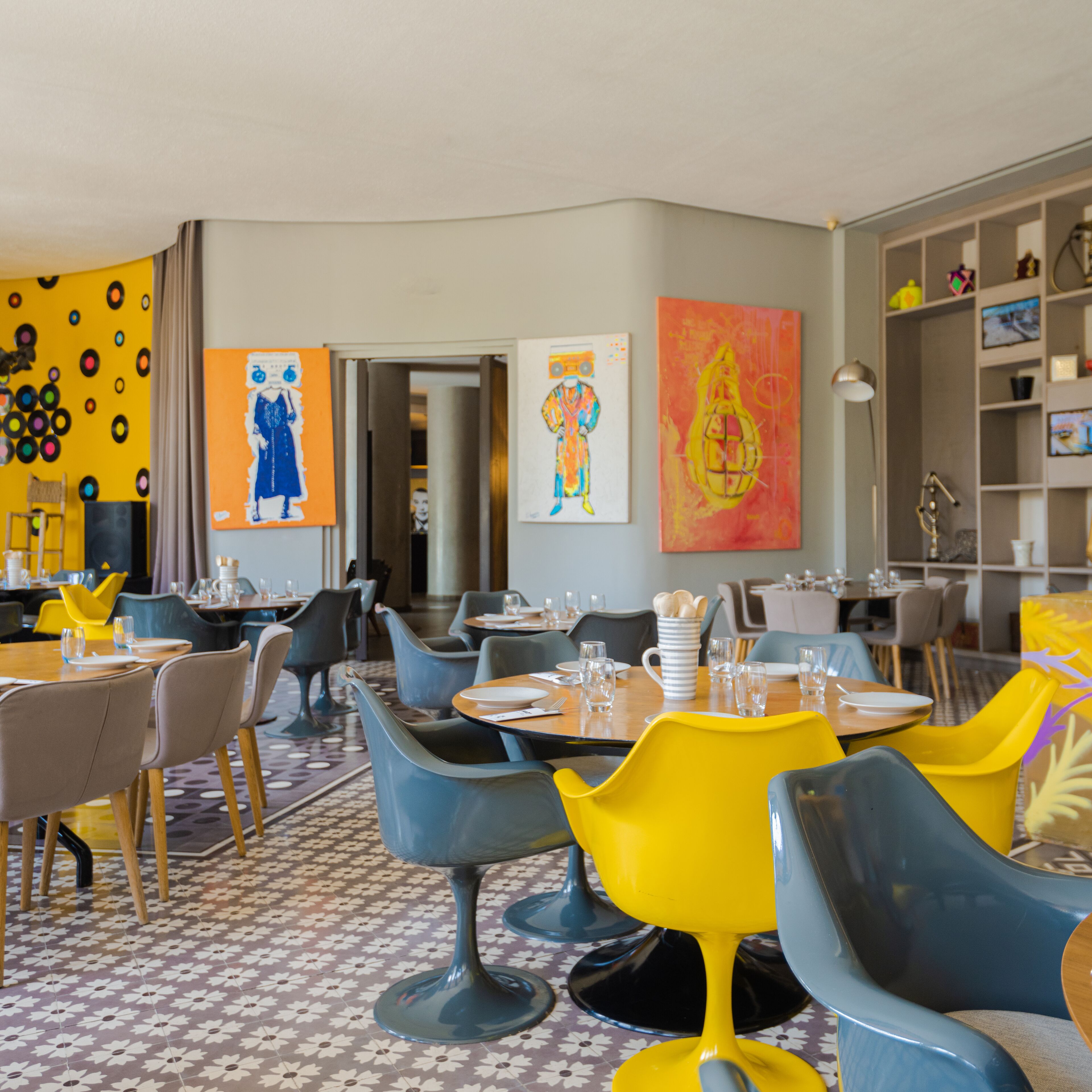 Zona pranzo con tavoli e sedie, opere d'arte alle pareti e pavimento decorato.
