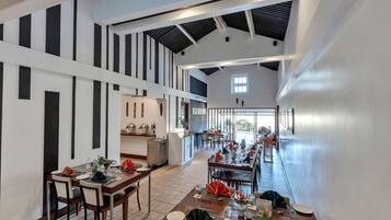 Un comedor espacioso con techos altos y decoración moderna, con mesas largas dispuestas para varios comensales.