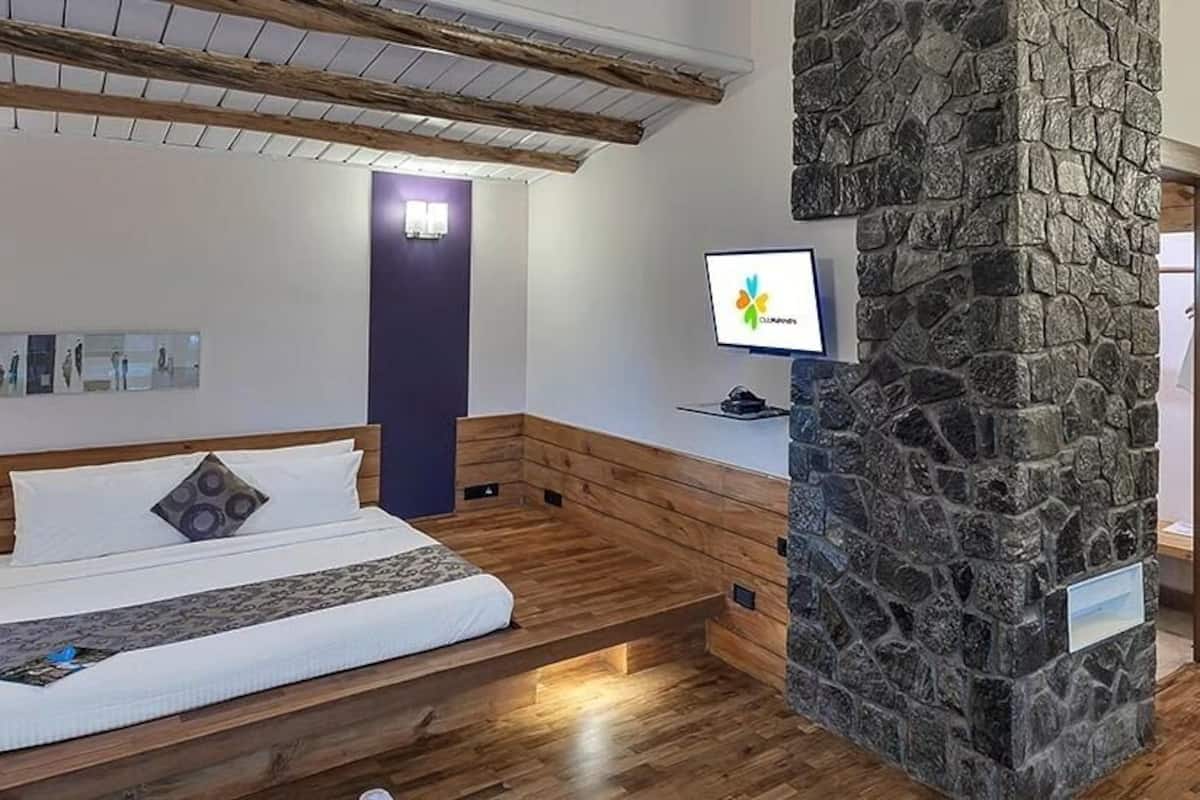 Un dormitorio con una cama, un pilar de piedra, un escritorio con computadora y un banco.