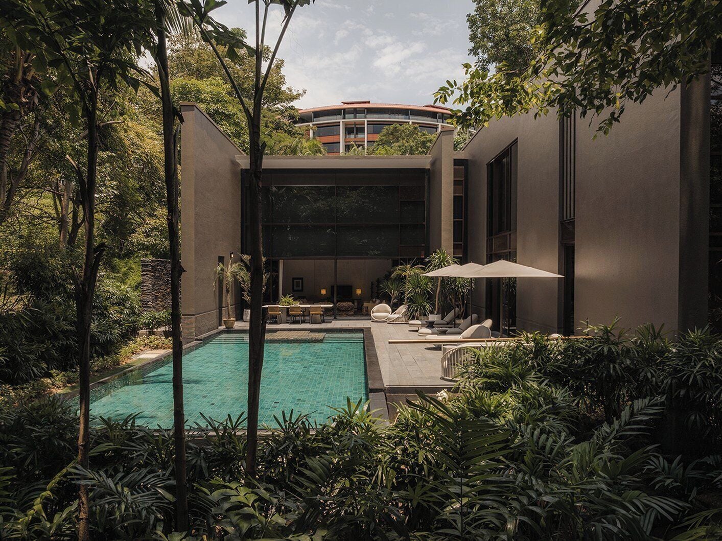 A modern building with a swimming pool surrounded by lush greenery.