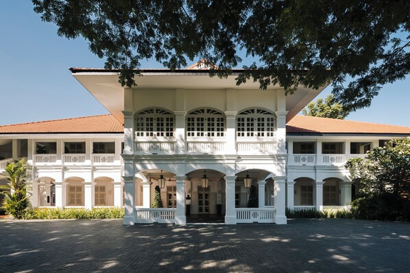 Un edificio grande de estilo colonial blanco, con varios balcones y ventanas arqueadas.